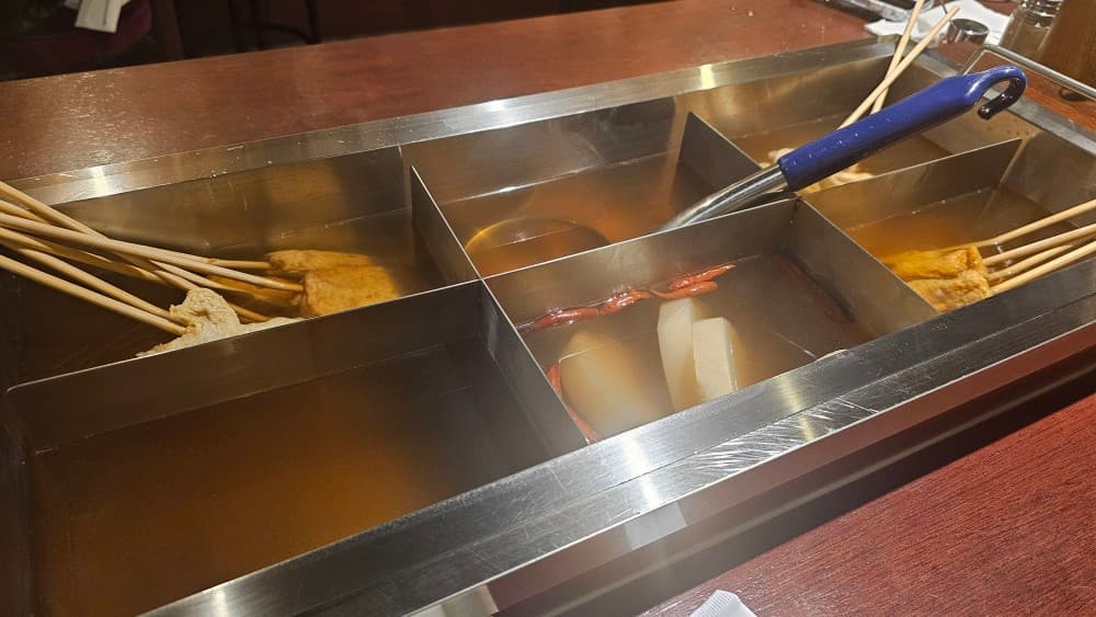 수원 꼬순네 어묵 바 테이블 위 정갈하게 담긴 어묵 꼬치와 시원한 무 국물, 혼술하기 좋은 아늑한 분위기.