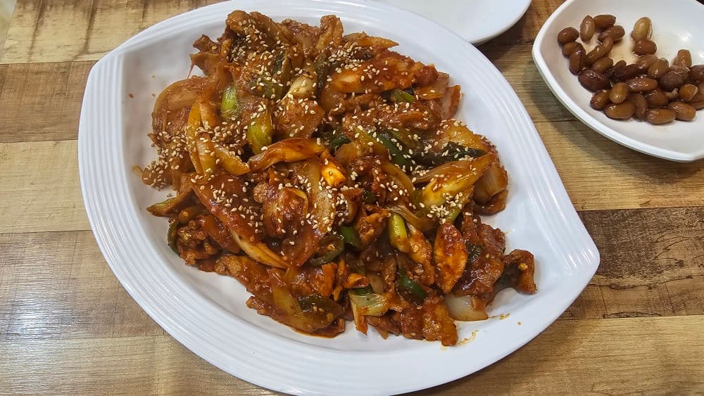 밤샘포차의 깨가 뿌려진 매콤한 제육볶음과 땅콩조림, 혼술하며 즐기기 좋은 든든한 안주 구성