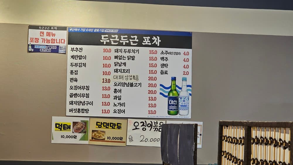 두근두근포차 벽면에 부착된 다양한 안주 메뉴판. 부추전, 닭발 등 혼술하기 좋은 저렴한 안주들이 가득합니다.
