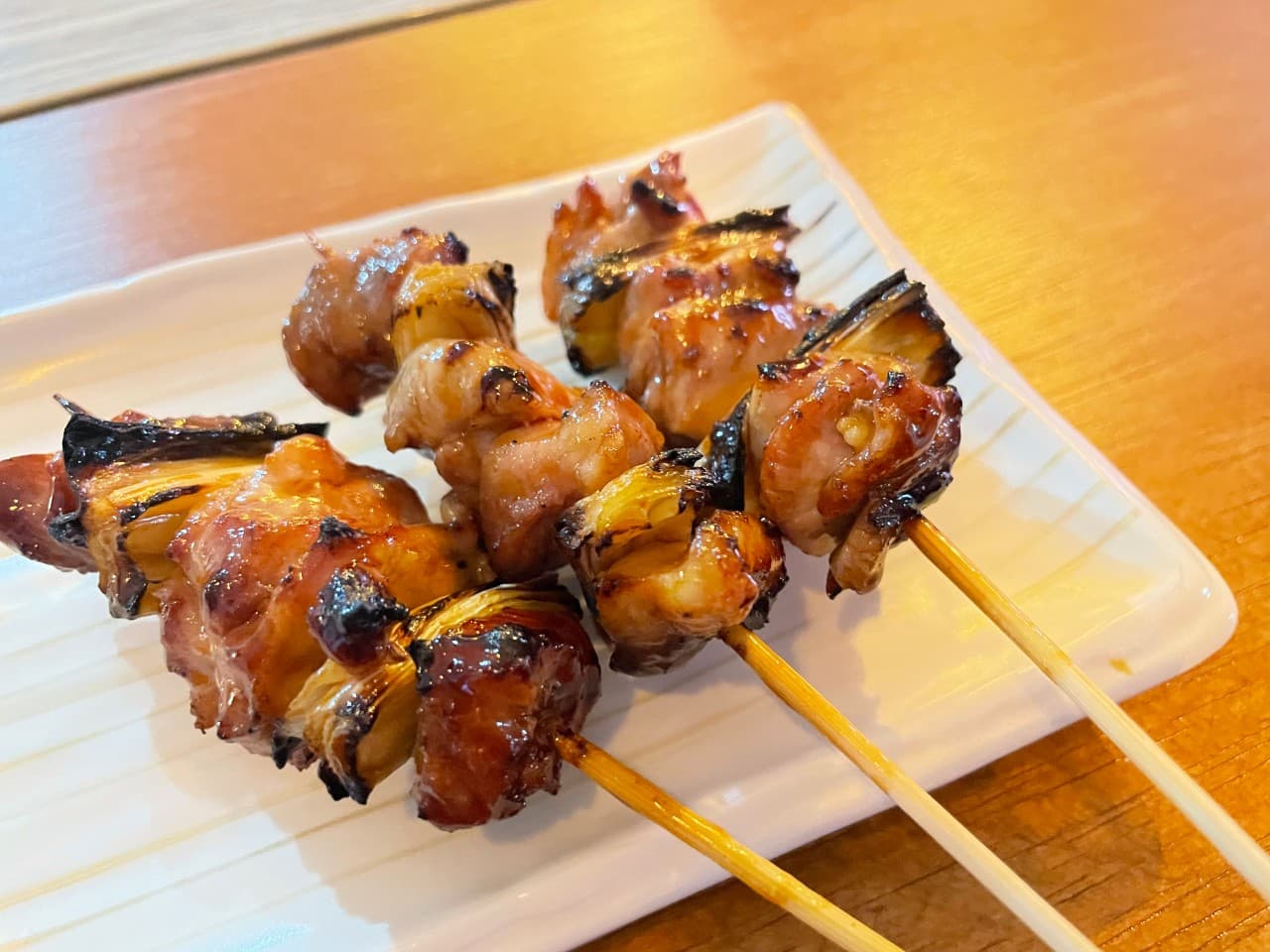 서울 동대문구 야키토리 지도리의 노릇하게 구워진 닭대파 꼬치구이. 윤기 흐르는 소스와 불향 가득한 야키토리가 하얀 접시에 담겨 있어, 천호대로 인근에서 조용히 혼술이나 혼밥을 즐기기에 좋습니다.