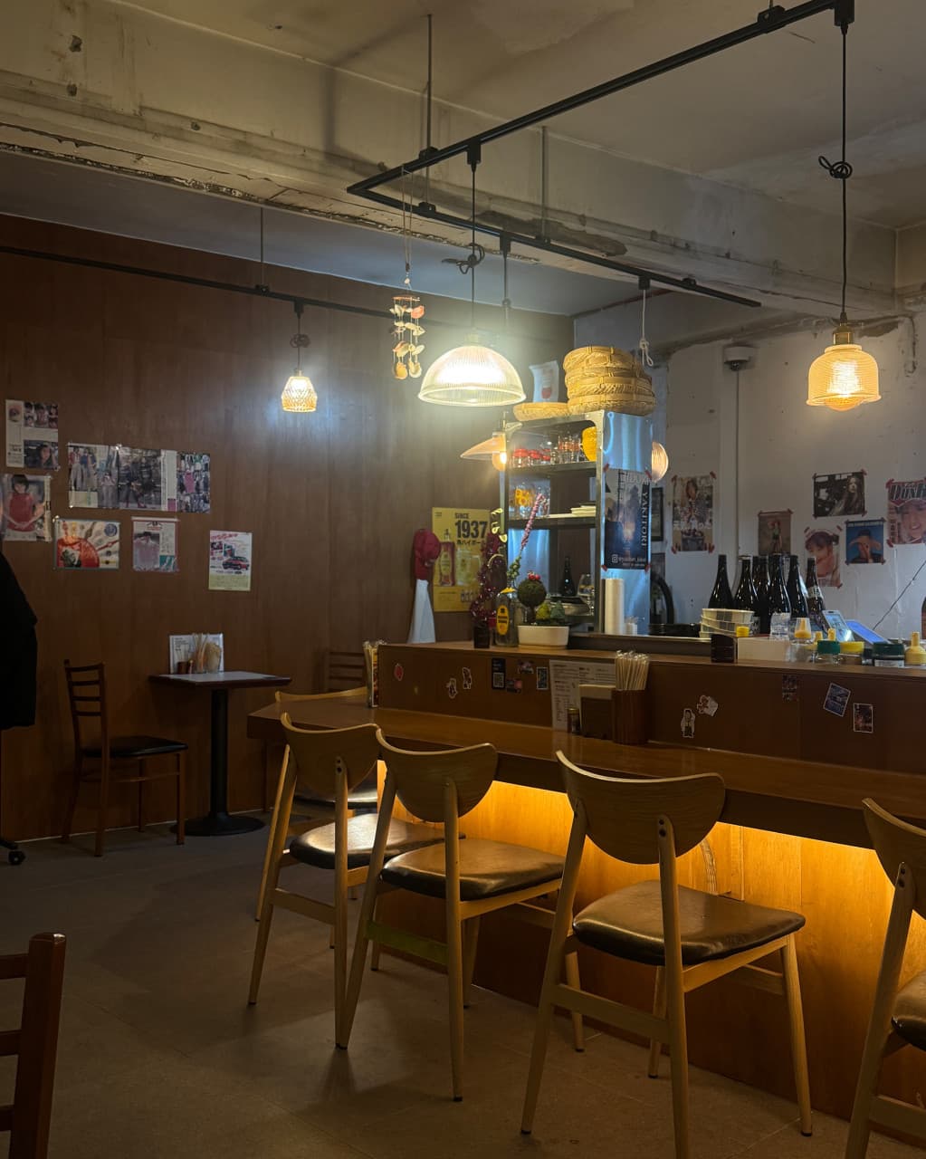 서울 동대문구 천호대로87길 13-3에 위치한 야키토리 지도리 내부. 따뜻한 조명의 목재 카운터석이 마련되어 혼술과 혼밥을 즐기기 좋은 아늑한 술집 분위기입니다. 벽면의 빈티지 포스터와 정갈한 인테리어가 돋보이는 공간입니다.