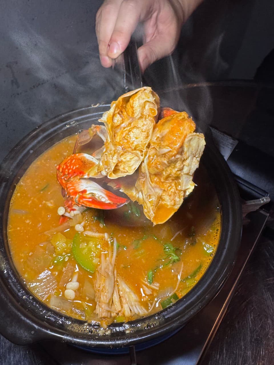 부산진구 가야대로 부엉이포차에서 김이 모락모락 나는 꽃게탕의 살이 꽉 찬 꽃게를 들어 올리는 모습. 애호박과 버섯이 들어간 얼큰한 국물로 혼술하기 좋습니다. (주소: 부산광역시 부산진구 가야대로747번길 69)