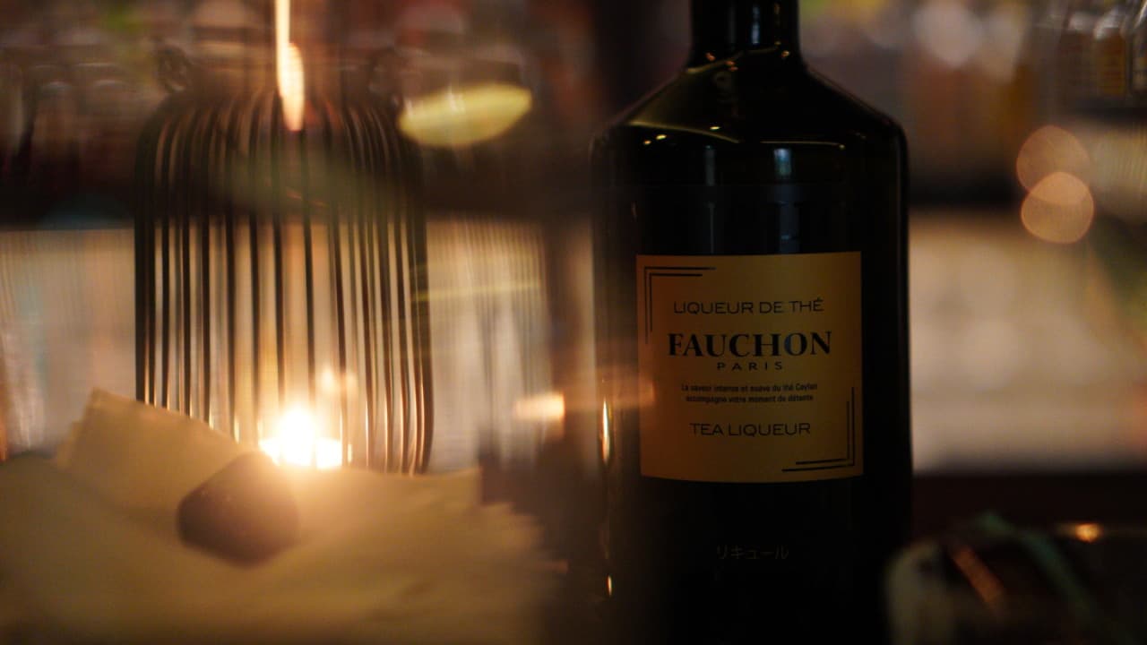 어두운 조명의 바 테이블 위 포숑 티 리큐르 병과 금속 케이지 속에서 타오르는 촛불