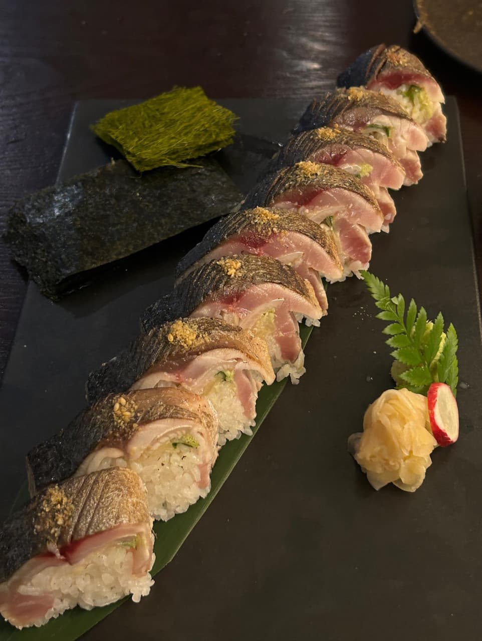 어두운 목재 테이블 위 검은 접시에 나란히 놓인 고등어 봉초밥과 감태, 김, 초생강. 혼자 즐기기 적당한 구성의 1인분 안주 차림.