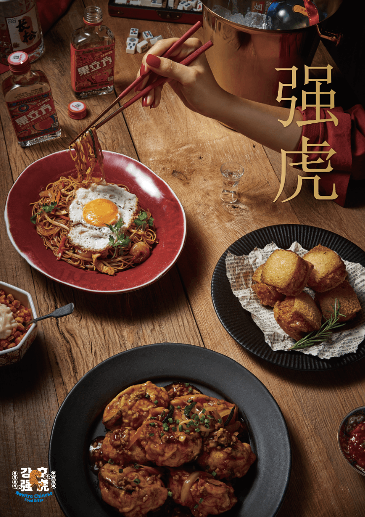 나무 테이블 위 계란 프라이를 얹은 볶음면과 튀김 요리들. 마작 패와 술병이 놓인 자리에서 홀로 젓가락으로 면을 들어 올리는 손.