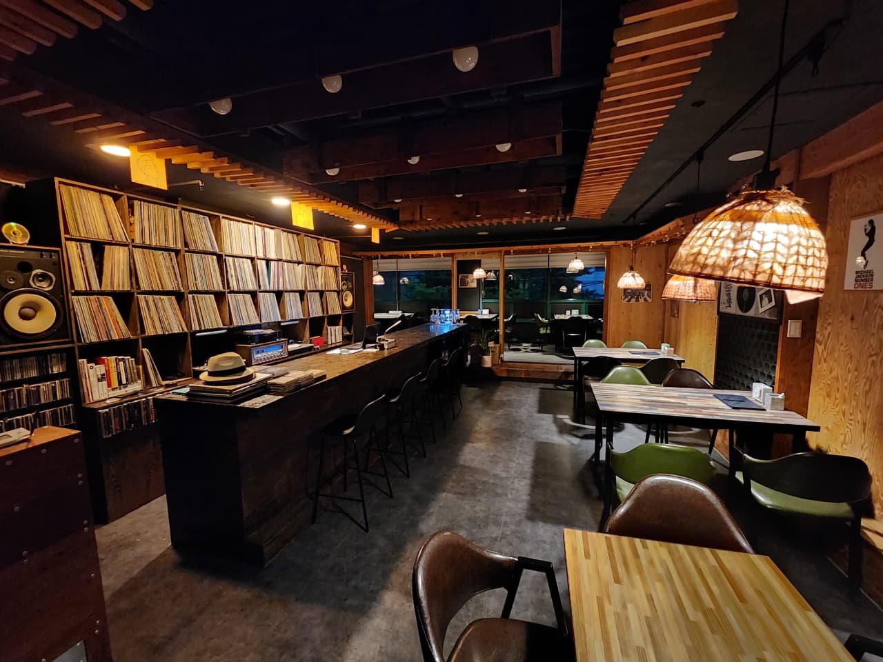 LP 레코드가 진열된 벽면을 마주한 긴 나무 카운터석과 1인용 높은 의자들이 배치된 바 내부 공간