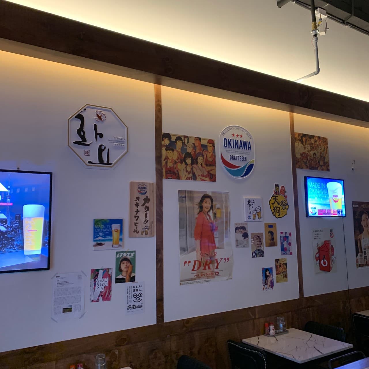 상단 간접 조명과 일본풍 포스터가 부착된 벽면 아래 1인용 대리석 무늬 테이블이 배치된 공간