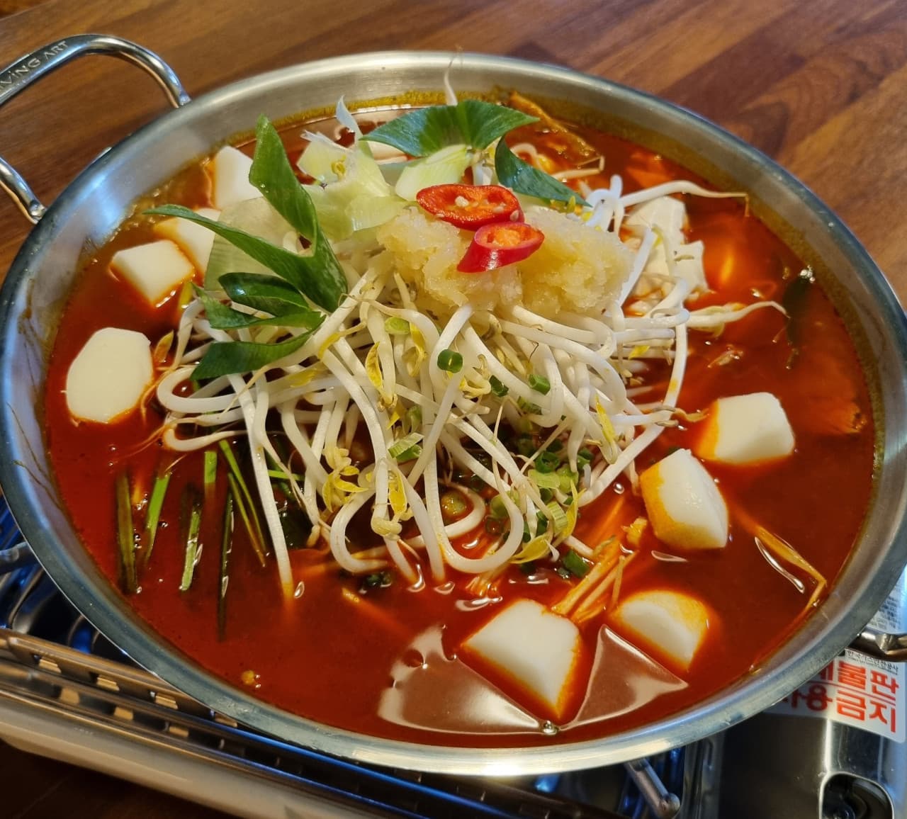 경기도 수원시 요리주점 배씨상회 수원스타필드 다찌석에 차려진 1인 전골. 가스레인지 위 빨간 육수에 숙주와 마늘이 가득 담긴 냄비가 놓인 혼술 상황.