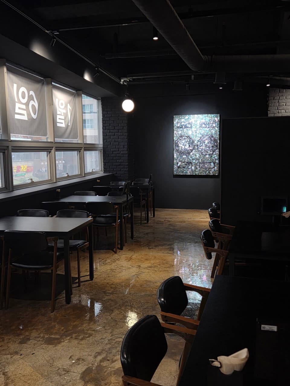 세종특별자치시 보듬3로 요리주점 랑 세종의 어두운 실내. 검은색 테이블과 1인석, 빛나는 자개 장식. 창가 로고 아래 낮은 조도가 유지되는 공간에서 즐기는 혼술 분위기