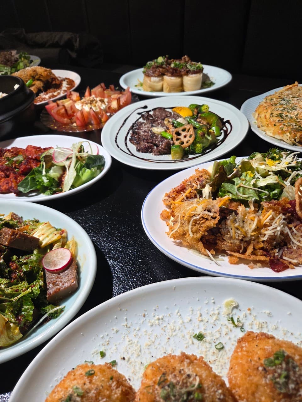 세종특별자치시 보듬3로 요리주점 랑 세종의 조명 아래 차려진 1인 안주들. 검은 테이블 위 바삭한 튀김과 고기 요리, 샐러드 질감이 돋보이는 혼술 상황.