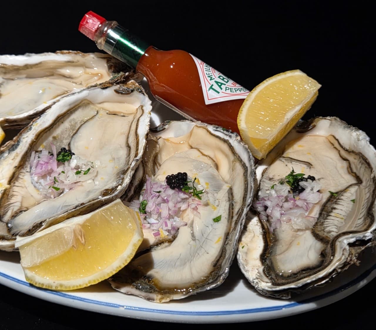 세종특별자치시 보듬3로 요리주점 랑 세종 다찌석의 1인 혼술 차림. 조명 아래 레몬과 타바스코 소스를 곁들인 생굴 석화가 놓인 상황을 보여줌.