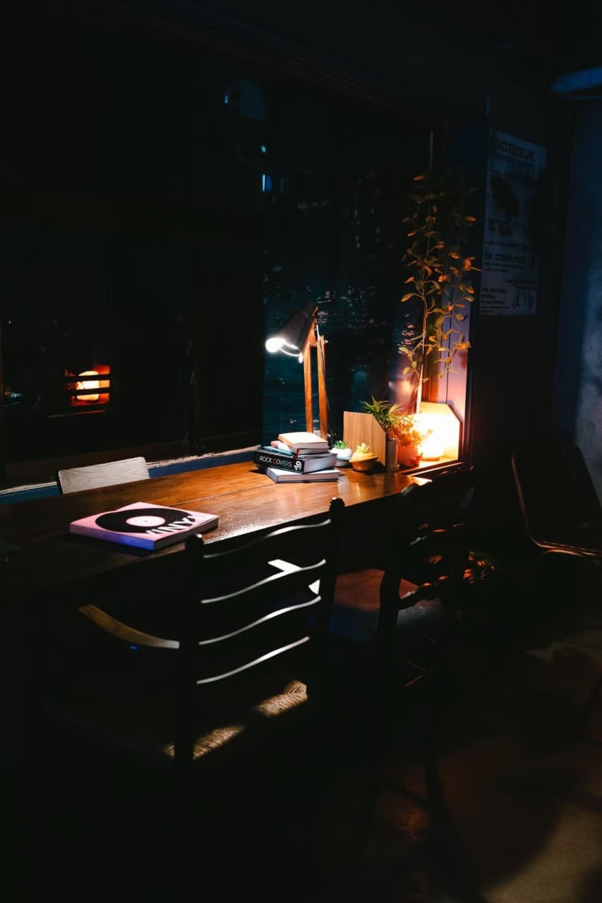 부산광역시 부산진구 페일블루닷 전포 바(Bar) - 스탠드 조명이 비추는 나무 다찌석에 책과 LP가 놓여 있는 1인 혼술 공간