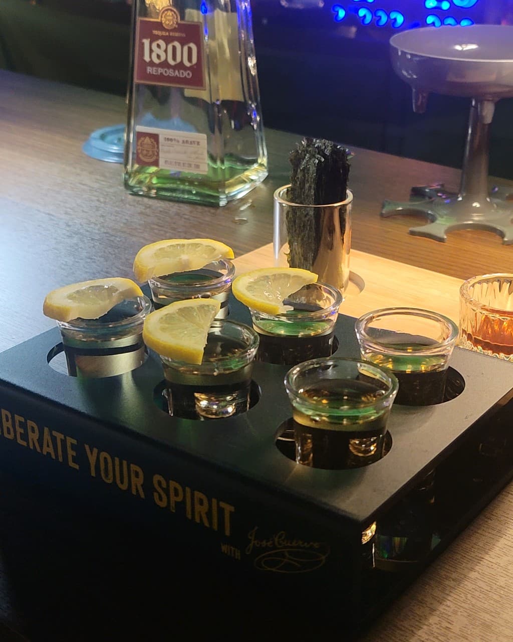 부산광역시 중구 펍송 인 광복 맥주 호프 다찌석에 놓인 1800 레포사도 데킬라와 레몬 슬라이스가 올라간 샷 세트. 어두운 실내 조명 아래 혼술용으로 차려진 술상과 마른 안주.