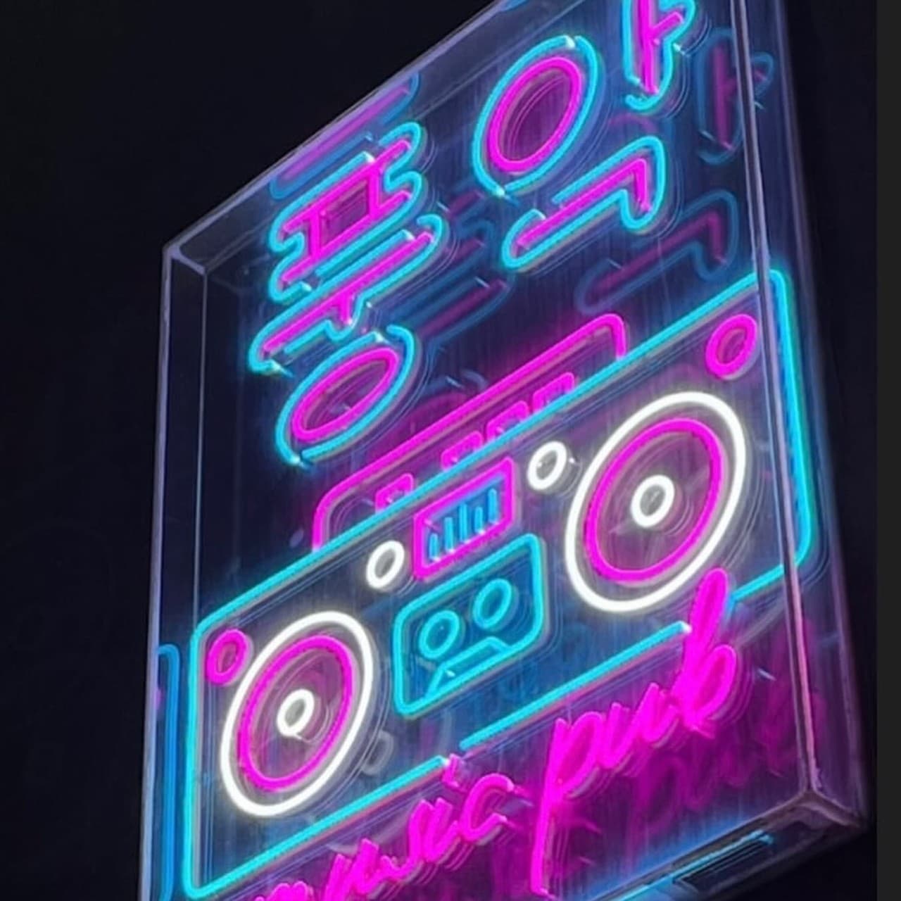 부산광역시 중구 혼술 맥주 호프 풍악 - 분홍색과 파란색 붐박스 네온사인 조명이 빛나는 입구. 1인 다찌석에서 음악을 들으며 맥주를 즐기는 분위기