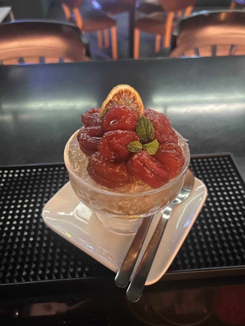 부산광역시 중구 혼술 바 선셋라운지 다찌석에 차려진 토마토 마리네이드. 조명 아래 유리 볼에 담긴 얼음과 붉은 토마토 절임의 질감이 보임.