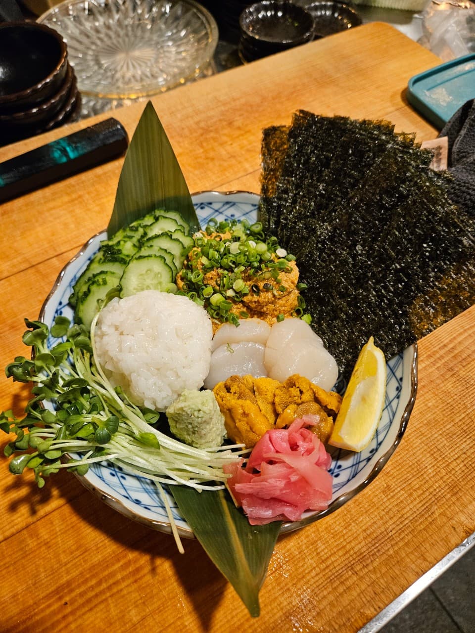 경상남도 창원시 로바타화염 이자카야 혼술 다찌석. 우니, 관자, 밥, 김이 담긴 1인 해산물 접시와 나무 테이블 위로 내리는 노란 조명의 질감.