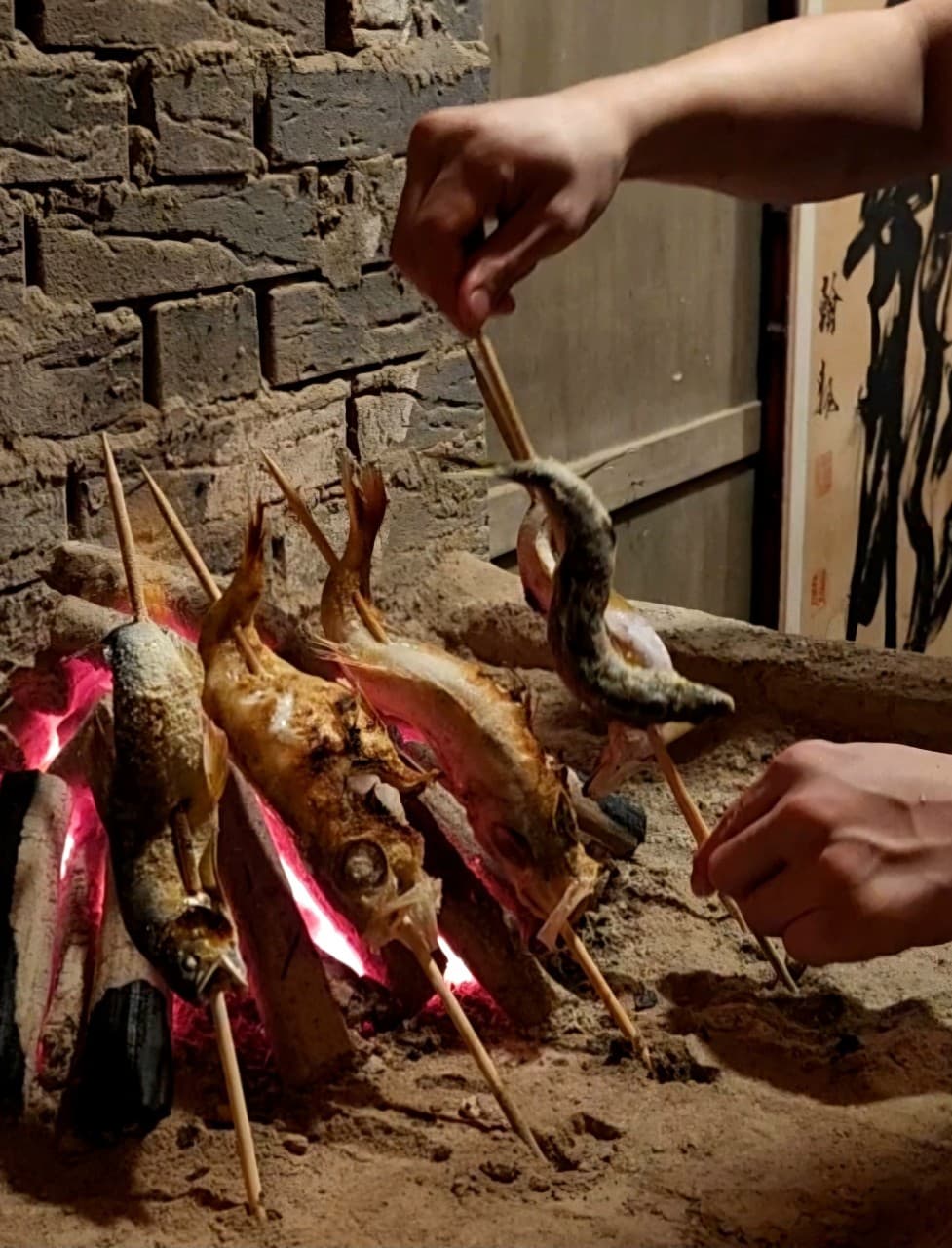 경상남도 창원시 이자카야 로바타화염의 붉은 숯불 조명 아래 바삭하게 익는 생선 원시구이. 다찌석 1인 혼술 상황의 조리 현장