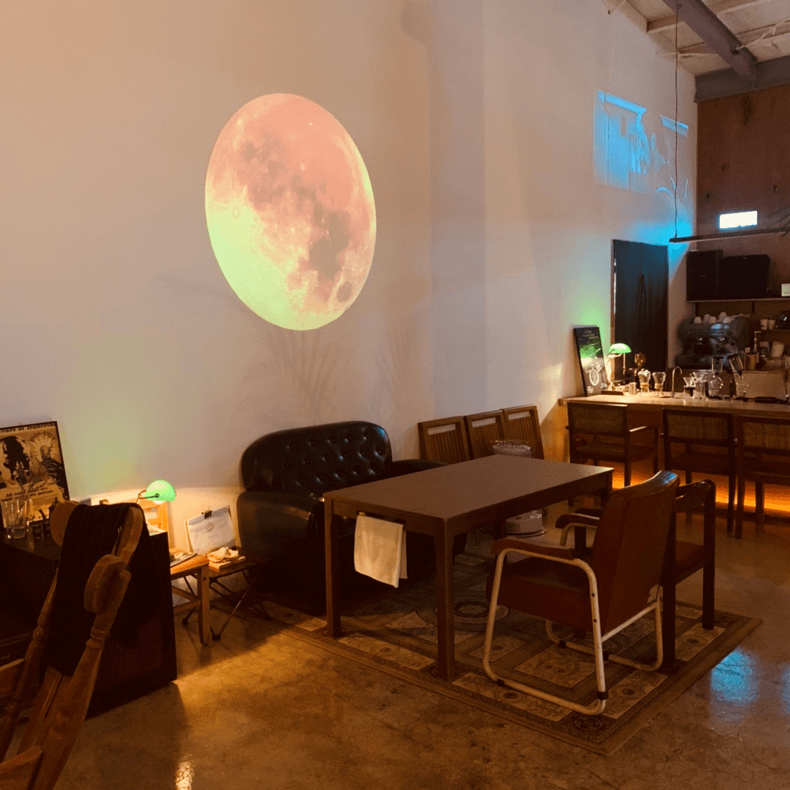 경상남도 사천시 진공관 벽면의 달 조명 아래 가죽 소파와 다찌석. 혼술에 적합한 바 테이블과 녹색 스탠드 조명이 배치된 내부