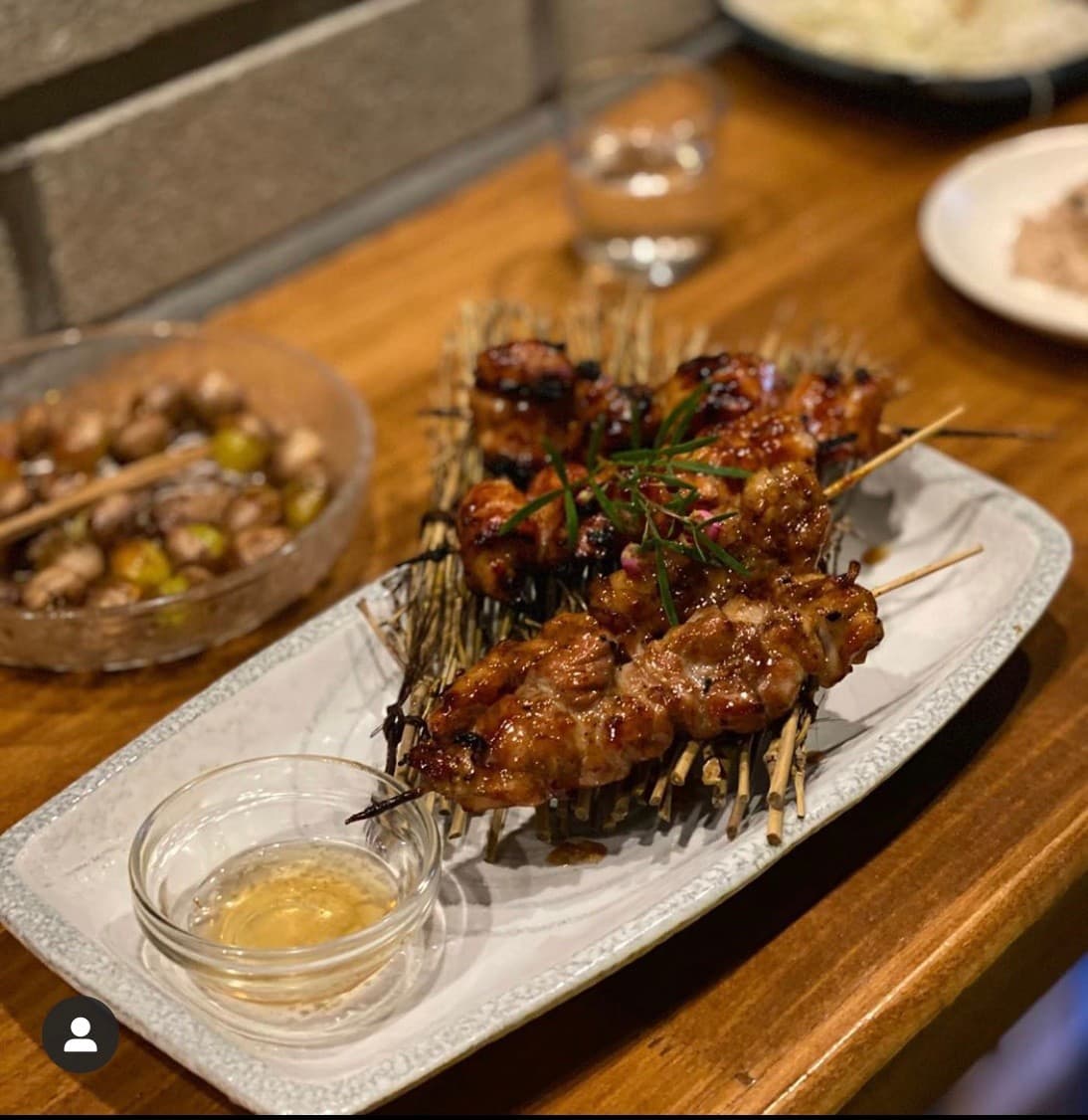 경상남도 진주시 주인집 하대본점 진주 이자카야 다찌석 나무 테이블 위 닭꼬치 구이와 소스, 은행볶음이 차려진 1인 혼술 상황