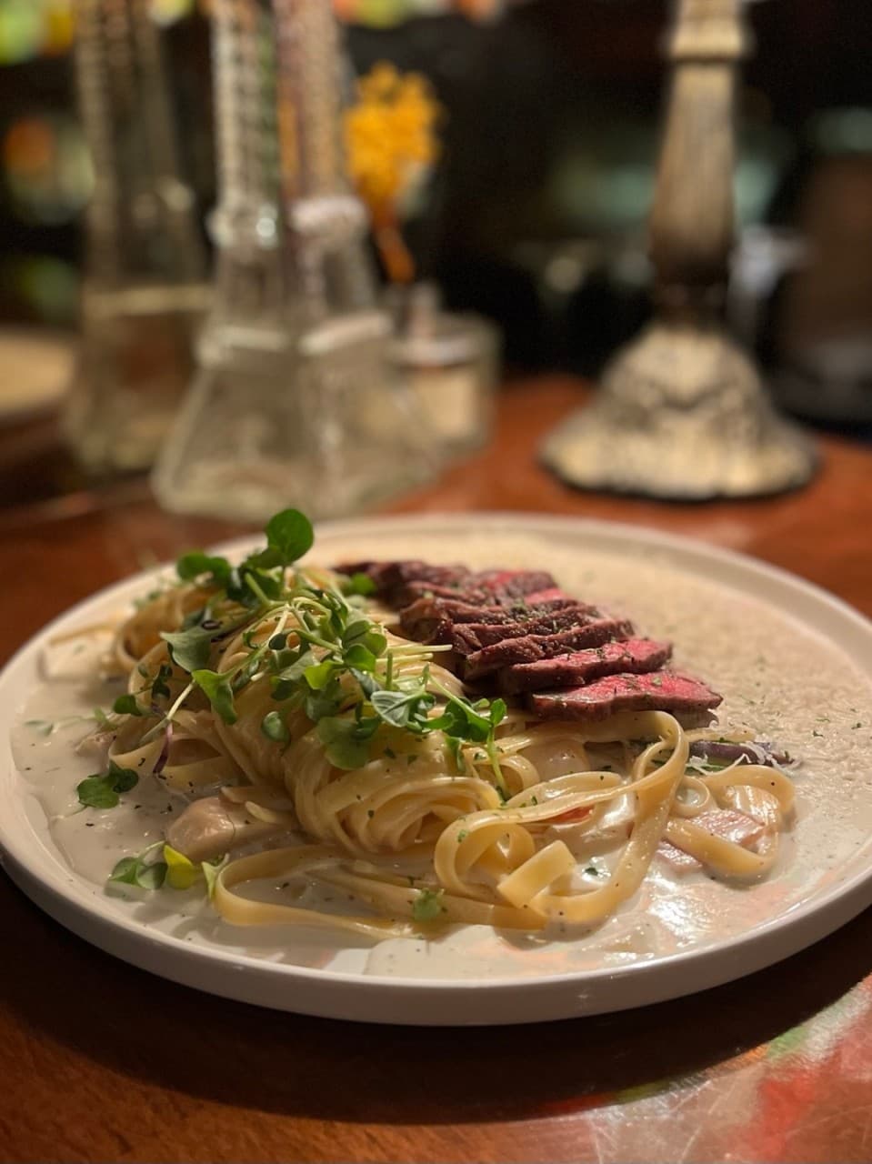 서울특별시 송파구 바 다빈치 잠실 바(Bar)의 조명 아래 1인 다찌석에 차려진 스테이크 크림 파스타. 꾸덕한 소스와 선홍빛 고기 질감이 선명한 혼술 상황.