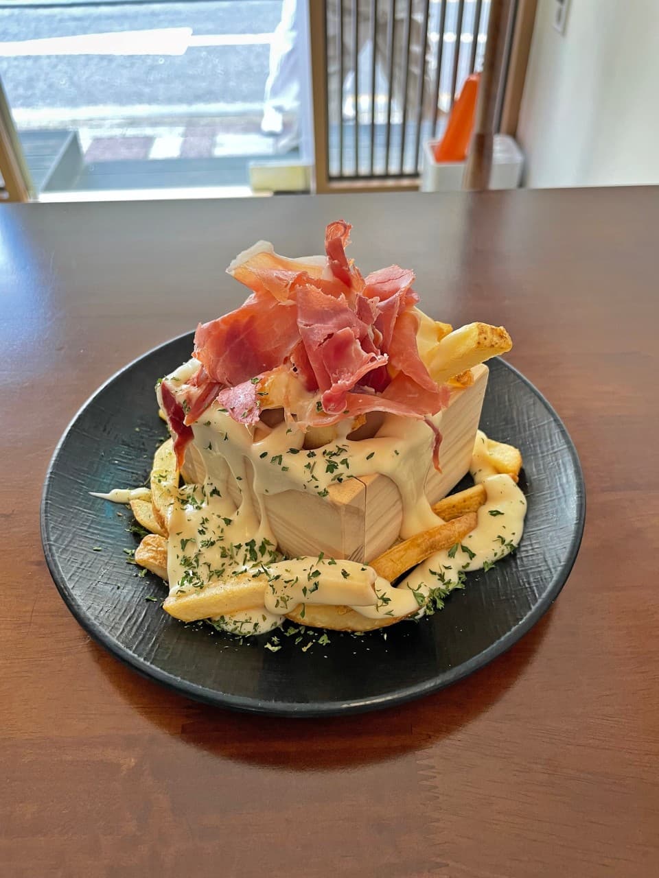 서울특별시 송파구 오뎅바모츠뎅 잠실 이자카야의 창가 다찌석. 나무 상자에 담긴 감자튀김과 크림 소스, 햄이 얹어진 1인 혼술 메뉴의 질감과 나무 테이블 위 채광이 비치는 상황.