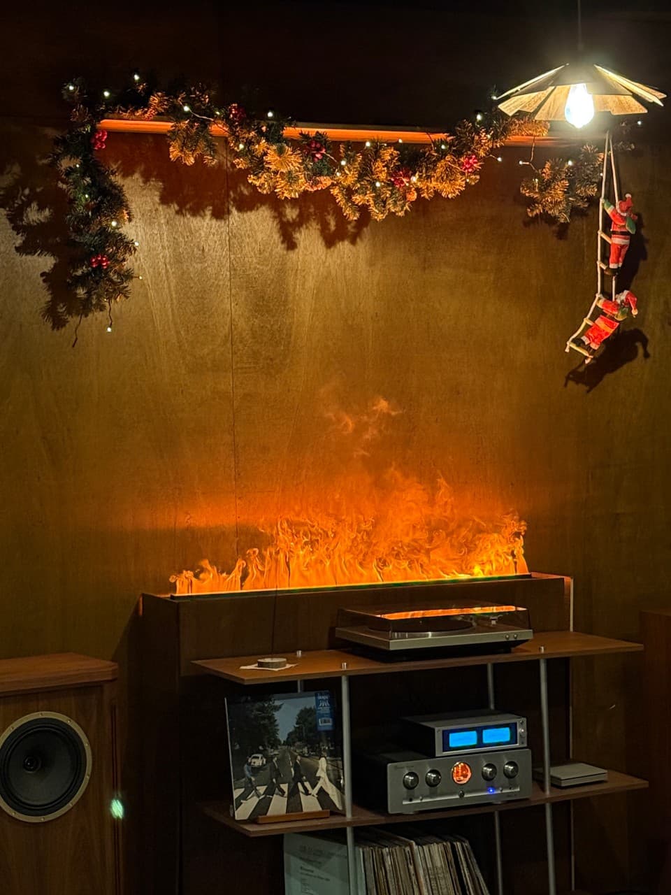 경상남도 진주시 와인 바 고효 진주. LP 플레이어와 불꽃 형태 조명, 비틀즈 앨범이 진열된 우드 선반 위로 크리스마스 장식이 배치된 1인 혼술 다찌석 공간.