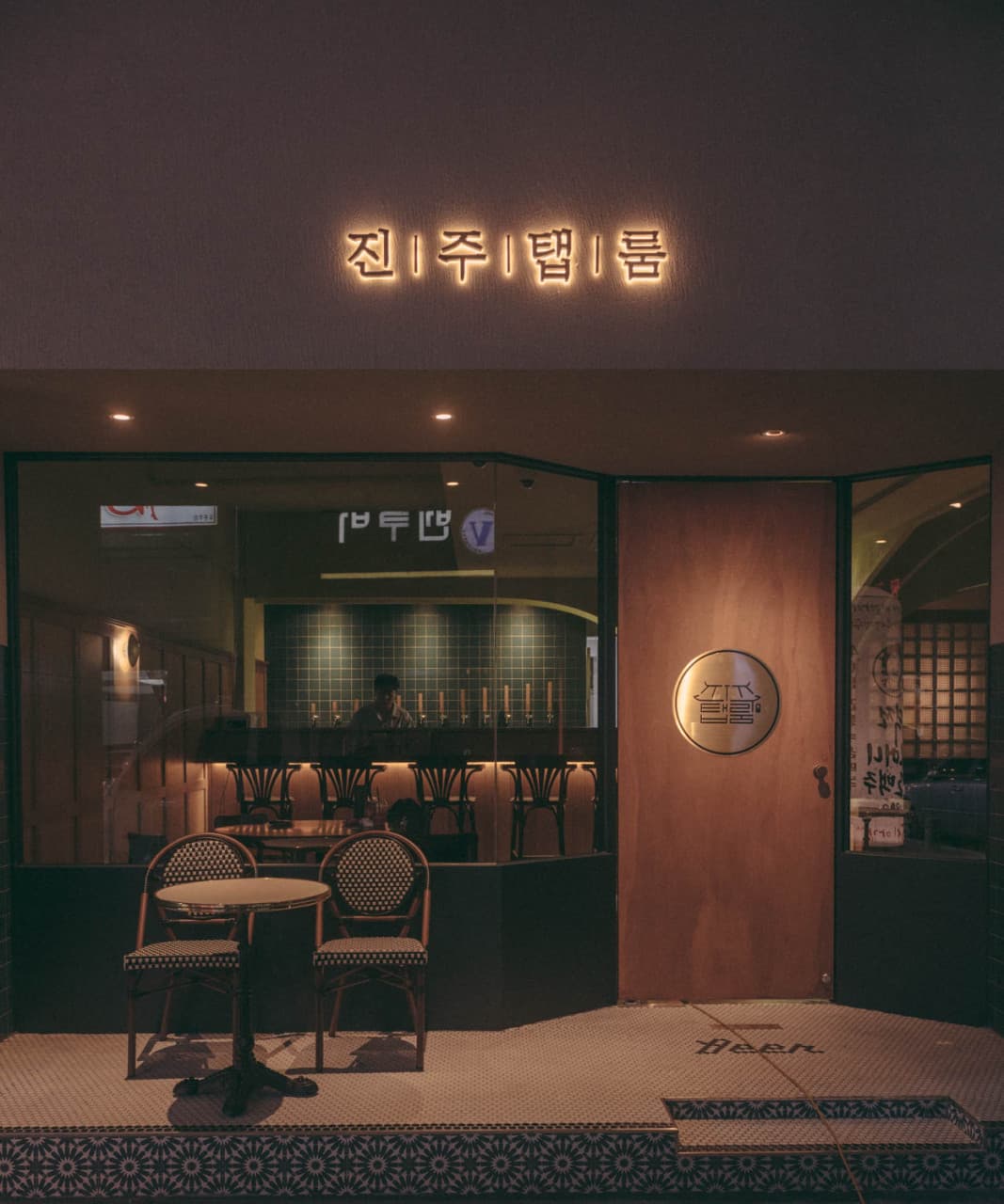 경상남도 진주시 진주탭룸 진주의 노란 조명이 켜진 입구. 혼술용 다찌석과 맥주 탭이 보이는 통유리창 내부와 야외 테이블이 비치된 기타 업종 매장 전경.