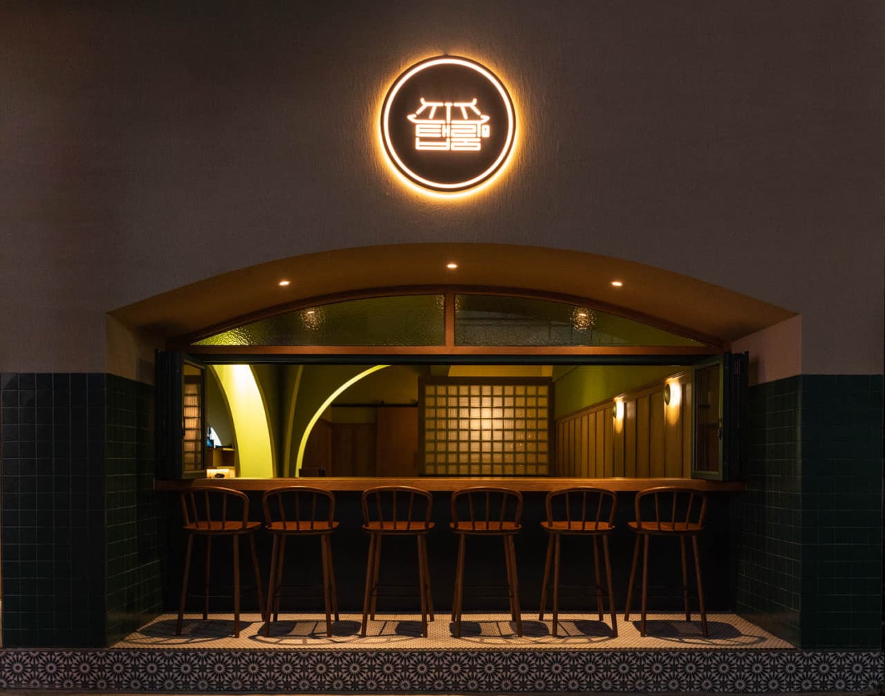 경상남도 진주시 진주탭룸 진주 매장 외부 다찌석에 놓인 1인용 나무 의자와 노란 원형 조명. 실내 조명이 비치는 바 카운터에서 혼술을 즐길 수 있는 기타 주점의 전경.