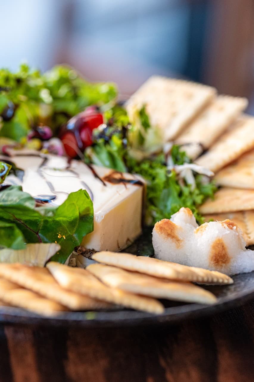 대전광역시 서구 마포십번 대전서구 이자카야 1인 혼술 안주. 발사믹 소스를 곁들인 치즈와 크래커, 샐러드가 다찌석 조명 아래 차려진 모습.