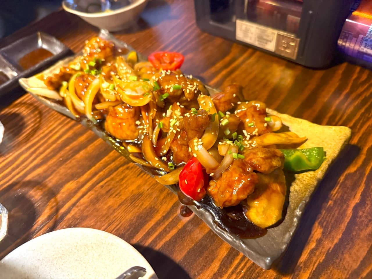 대전광역시 서구 이자카야 마포십번 대전서구 다찌석의 1인 안주. 나무 테이블 위 조명을 받아 윤기가 흐르는 고기 볶음 요리와 채소가 놓인 혼술 상황.