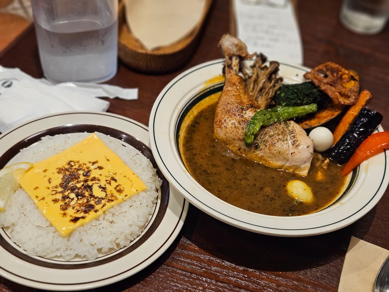 대전광역시 서구 요리주점 심도 대전서구 1인 다찌석. 낮은 조명 아래 구운 채소가 곁들여진 닭다리 수프카레와 토치로 익힌 치즈를 올린 밥이 차려진 혼밥 상황.