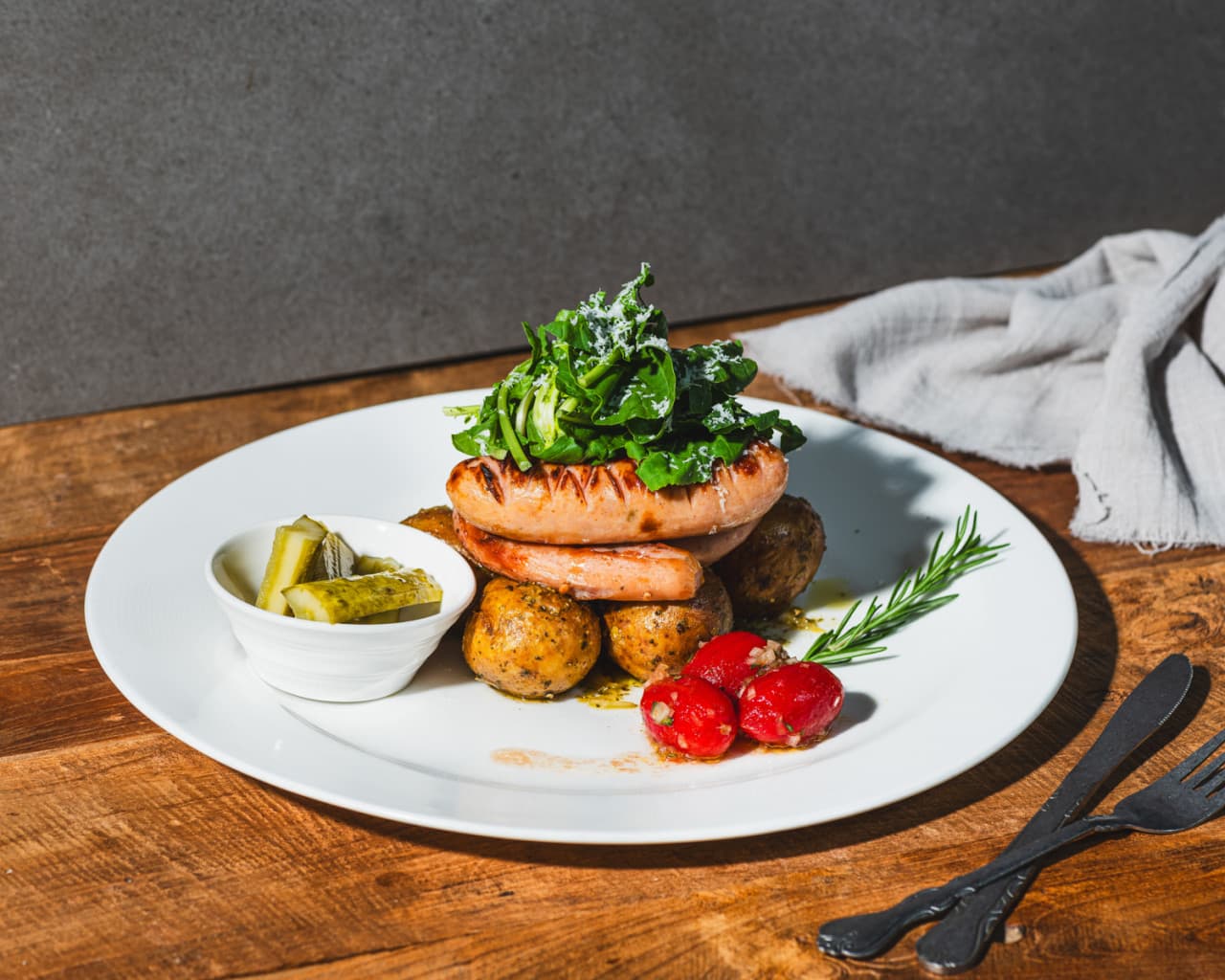 서울특별시 강남구 아이러브펍 강남본점 맥주,호프 다찌석에 차려진 1인 소시지 플레이트. 측면 조명이 비추는 목재 테이블 위 구운 감자와 소시지의 질감이 강조된 혼술 상황.