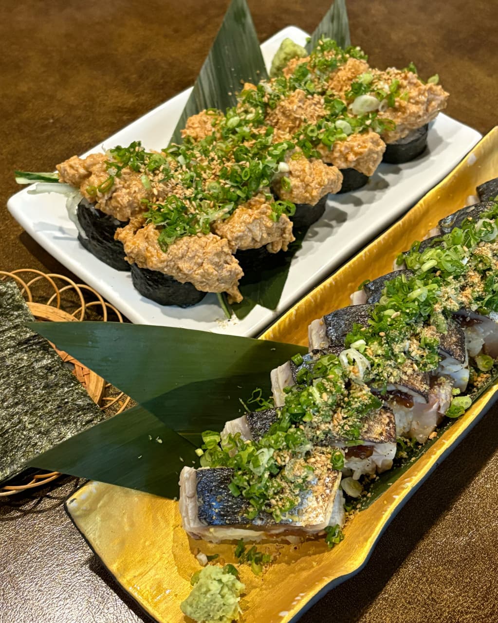 대구광역시 중구 삼덕동 우미노 이자카야 다찌석 조명 아래 놓인 고등어 봉초밥과 아귀간 마끼. 쪽파와 깨를 얹은 음식의 질감이 강조된 1인 혼술 상황.