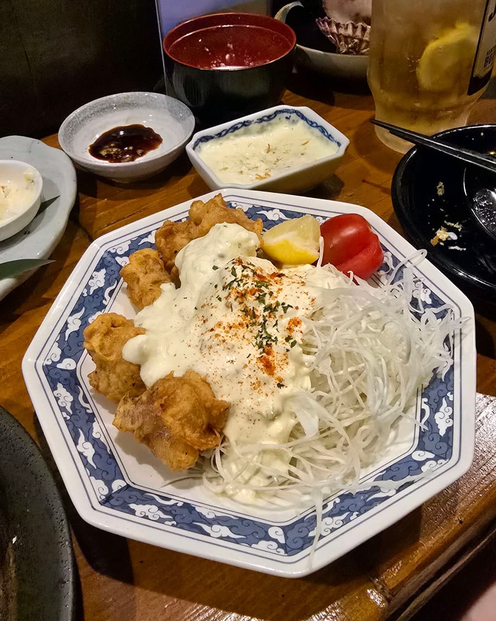 대구광역시 중구 삼덕동 우미노 이자카야 나무 다찌석 1인 혼술 차림. 하얀 소스를 얹은 치킨난반과 하이볼, 채 썬 양배추가 낮은 조명 아래 놓인 구성.