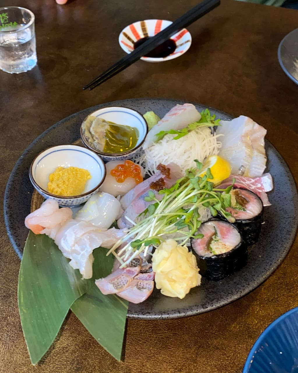 대구광역시 중구 이자카야 삼덕동 우미노 다찌석 조명 아래 차려진 1인 모듬 사시미. 투명한 생선회 질감과 마키, 소주잔이 놓인 혼술 현장.