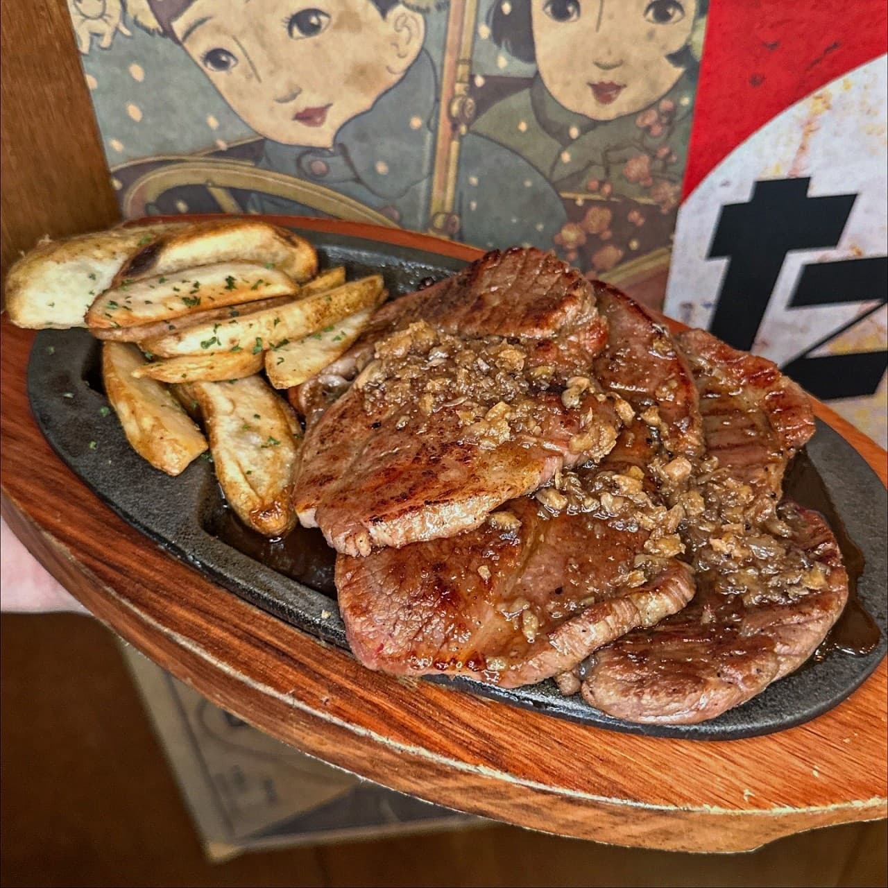 서울특별시 강남구 쿄코코 신논현 이자카야 다찌석에서 즐기는 1인 혼밥. 뜨거운 철판 위 마늘 토핑을 올린 고기 요리와 웨지 감자가 차려진 구성