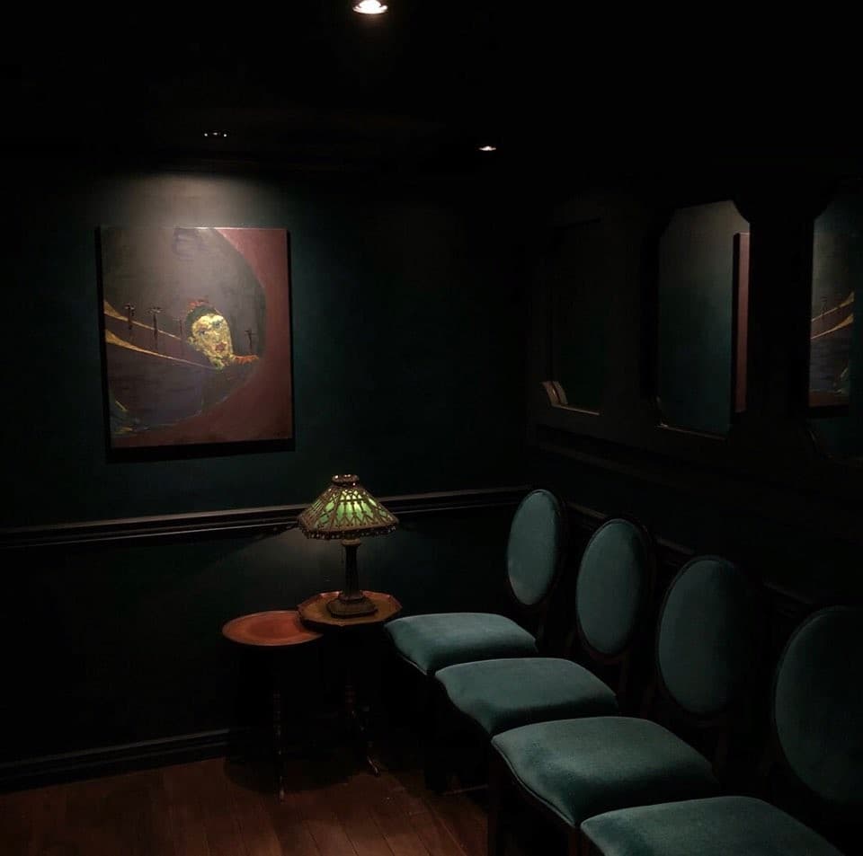 서울특별시 강남구 어글리 강남 바(Bar)의 빈티지 조명과 벨벳 소재 1인 좌석. 벽면의 회화 작품 아래 낮은 조명으로 조성된 혼술 공간의 내부 배치.