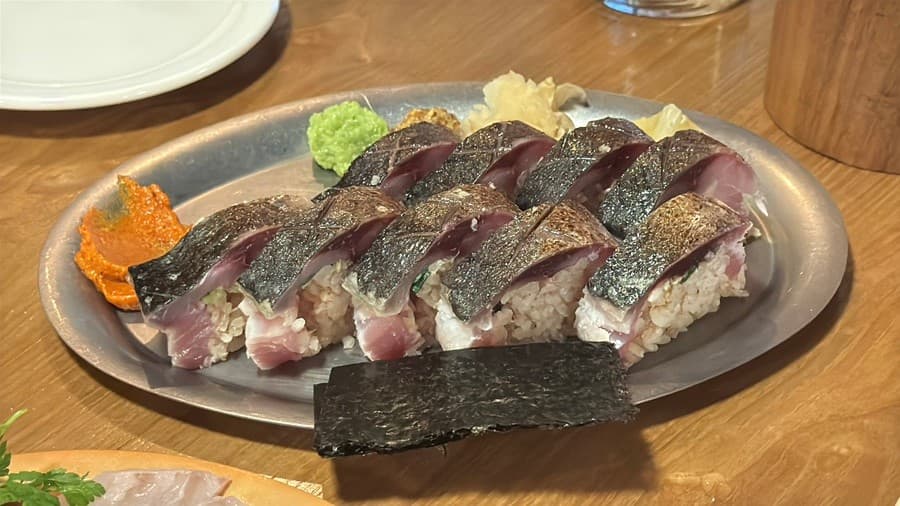 인천광역시 남동구 이자카야 쇼텐 구월점 인천 나무 다찌석 1인 혼술. 은색 접시 위 고등어 봉초밥의 표면 질감과 와사비가 조명을 받는 상황.