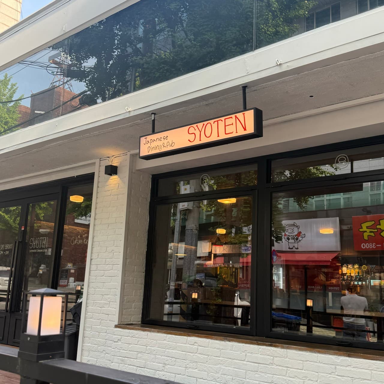 인천광역시 남동구 쇼텐 구월점 인천 이자카야의 흰색 벽돌 외관과 검은 창틀. 유리 너머 비치는 은은한 조명 아래 1인 다찌석과 혼술 가능한 일식 주점 입구.