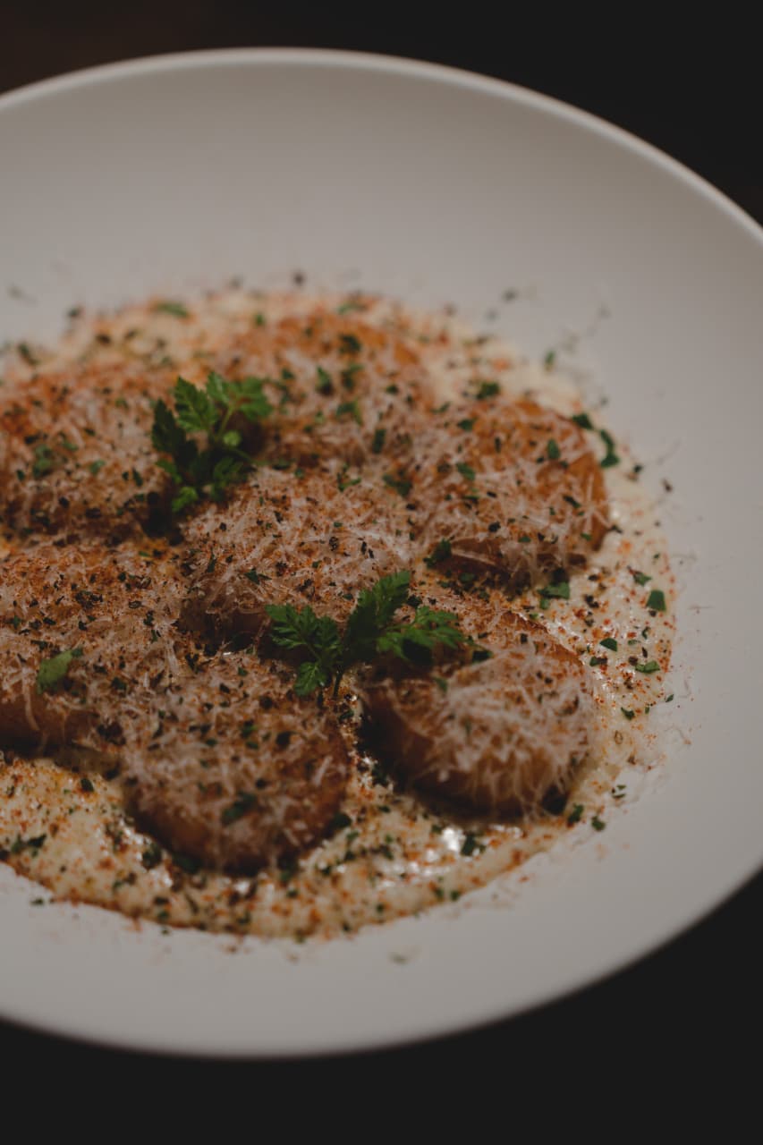 서울특별시 마포구 미티 모던바 - 낮은 조명 아래 크림 소스와 치즈가 뿌려진 1인 뇨끼가 놓인 다찌석 혼술 상황