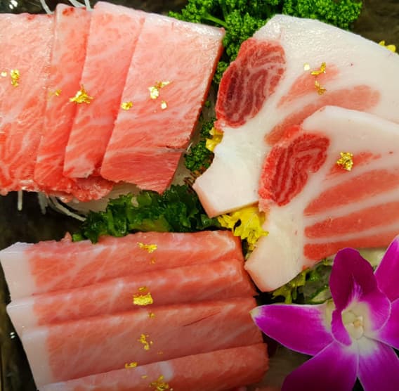 서울특별시 강서구 신경섭의 인생참치 다찌석에서 즐기는 1인 혼술. 금가루가 뿌려진 선명한 선홍빛 참치 사시미와 기타 부위가 조명 아래 정갈하게 차려진 상황.