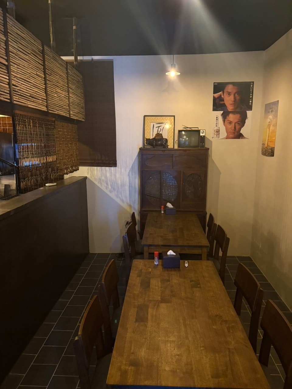 부산광역시 동구 이자카야 아지센 초량 내부. 천장 조명이 비추는 나무 테이블과 다찌석, 벽면의 포스터가 어우러진 1인 혼술 공간.