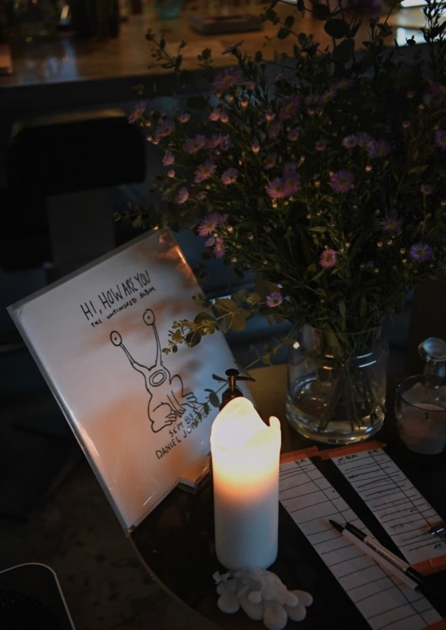 경상북도 경주시 오아시스 경주 황리단길 와인바의 다찌석. 촛불 조명과 보라색 꽃병이 놓인 테이블에서 캐릭터 포스터를 배경으로 1인 혼술을 하는 상황