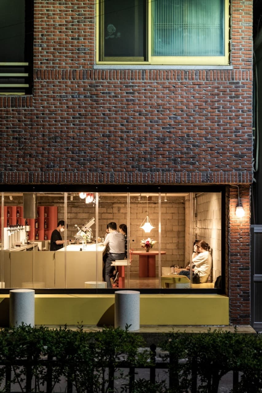 경상북도 경주시 맥주 호프 흐흐흐 경주 - 붉은 벽돌 건물 통유리 너머 노란 조명 아래 카운터 다찌석과 1인석에서 혼술을 즐기는 사람들과 내부 전경