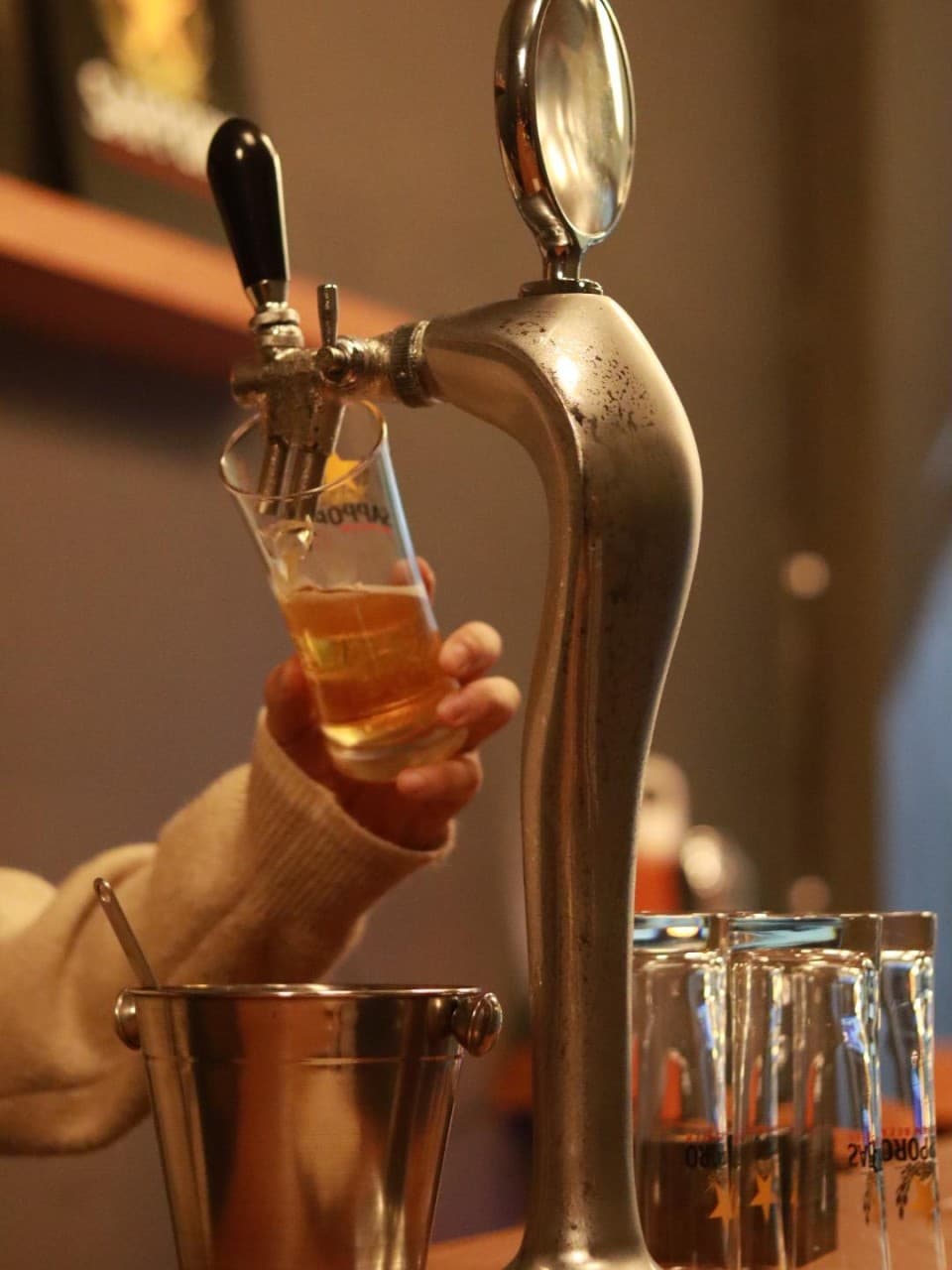 경상북도 경주시 혼술바 포 경주 다찌석에서 생맥주를 따르는 모습. 스테인리스 맥주 탭과 유리잔이 놓인 1인 바(Bar) 내부의 노란 조명 아래 혼술 상황.