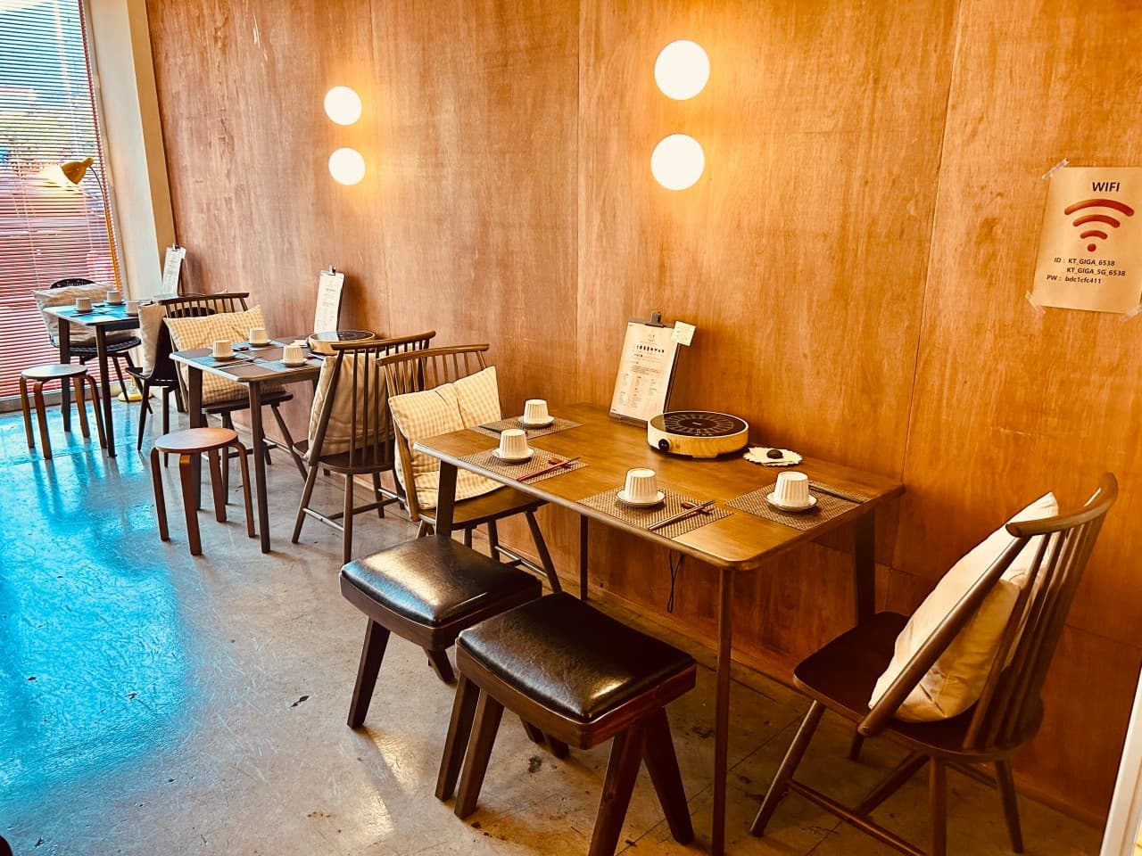 경상북도 경주시 텐고쿠 경주 - 원형 조명과 나무 벽면 앞 1인 혼밥 테이블. 인덕션과 식기가 세팅된 기타 업종 식당의 내부 구성.