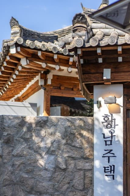 경상북도 경주시 황남주택 경주 맥주 호프 - 전통 한옥 기와와 돌담 아래 1인 혼술을 맞이하는 매장 입구와 세로형 간판 위 전구 조명