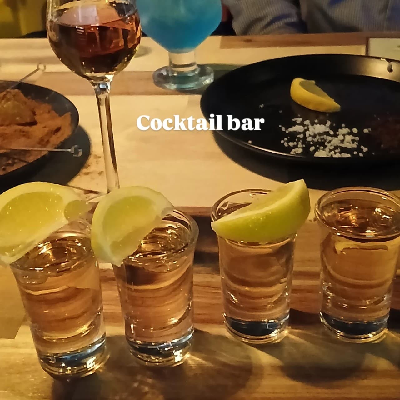 경상북도 경주시 페인터 닷츠 경주 바(Bar) 다찌석에 차려진 레몬 곁들인 데킬라 샷과 칵테일. 조명 아래 혼술 테이블 위 소금과 레몬 조각이 담긴 검은 접시 구성.