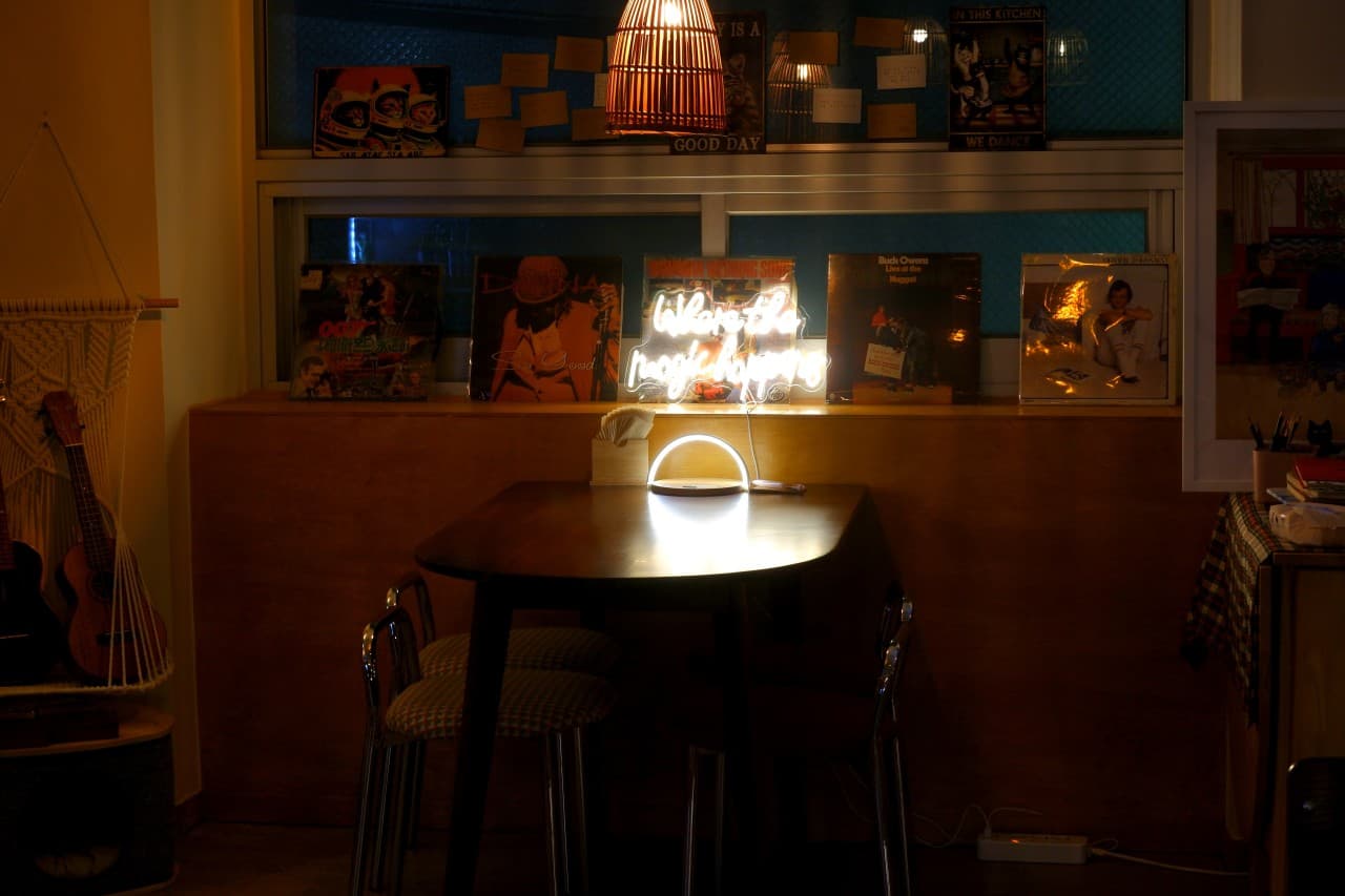 경상북도 포항시 맥주 호프 낮잠 - 오렌지빛 조명 아래 LP판과 네온사인이 위치한 1인 다찌석. 혼술을 위한 목재 테이블과 우쿨렐레가 놓인 내부 전경.