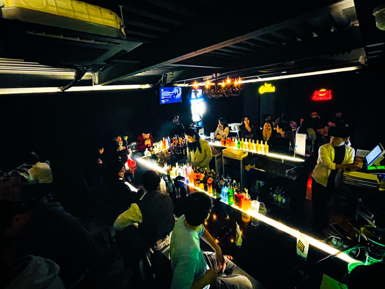 대구광역시 중구 고고비닐 대구 와인바의 밝게 빛나는 긴 다찌석 카운터에서 즐기는 1인 혼술. 어두운 실내 속 조명이 비치는 다양한 술병들과 바텐더가 대기하는 공간